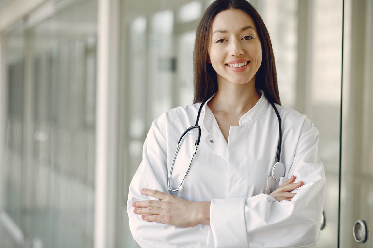 stats-img Portrait of a smiling female doctor with arms crossed and stethoscope in a hospital corridor.