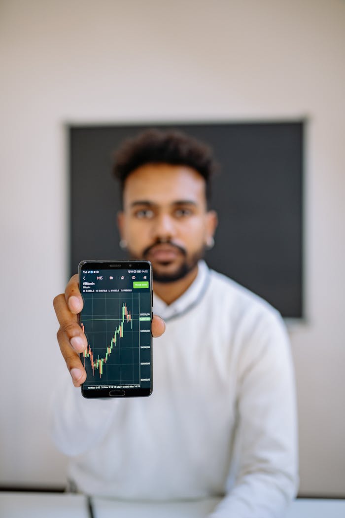 creative-approach-img Man holding smartphone with stock market chart, focusing on financial growth.